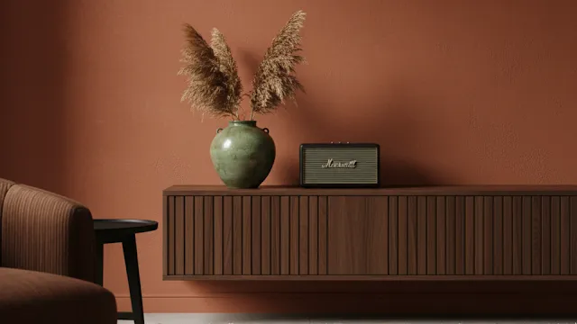 A minimalist room showcasing the "brown-aissance" with a deep terracotta wall, a sleek walnut media console, and a brown corduroy armchair.